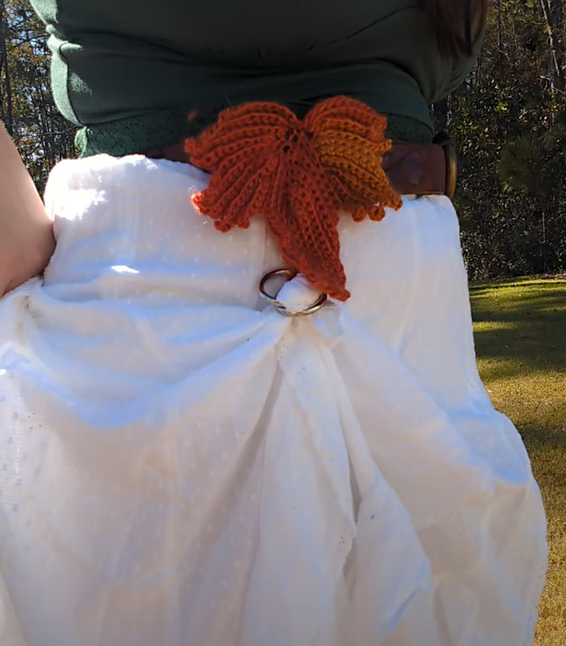 Crocheted fall leaf mounted on a belt, holding up a white skirt