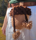 A crocheted acorn bag with a pom pom drawstring
