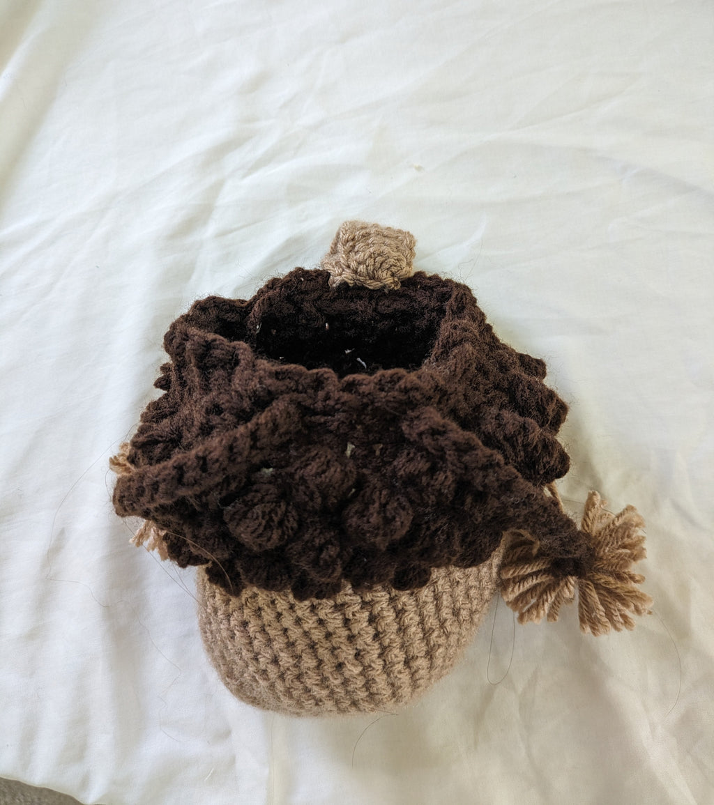 Crocheted acorn-shaped container on a white surface