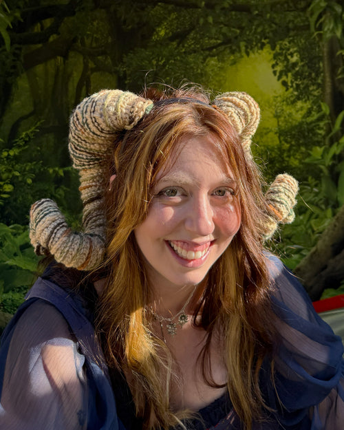 Person wearing ram horns in a forest setting